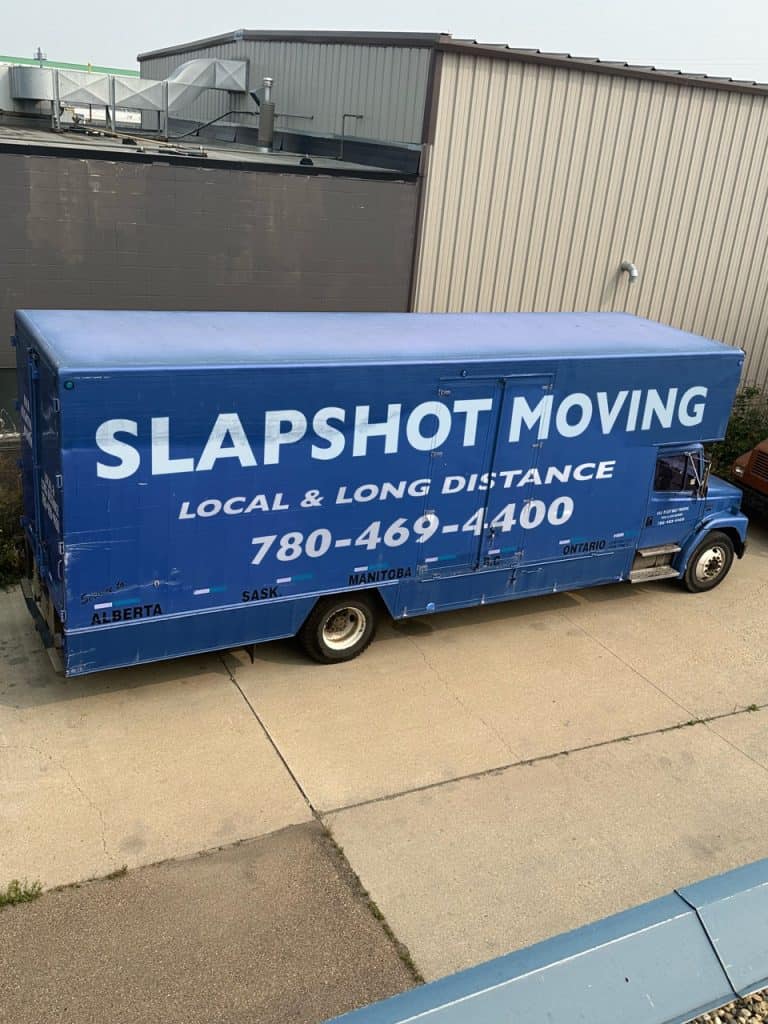 Blue Slapshot Moving truck parked beside warehouse